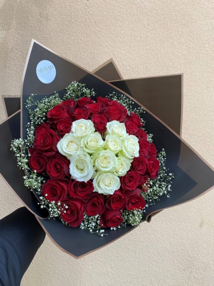 A lush bouquet of hearty red roses with vibrant green leaves, beautifully arranged.